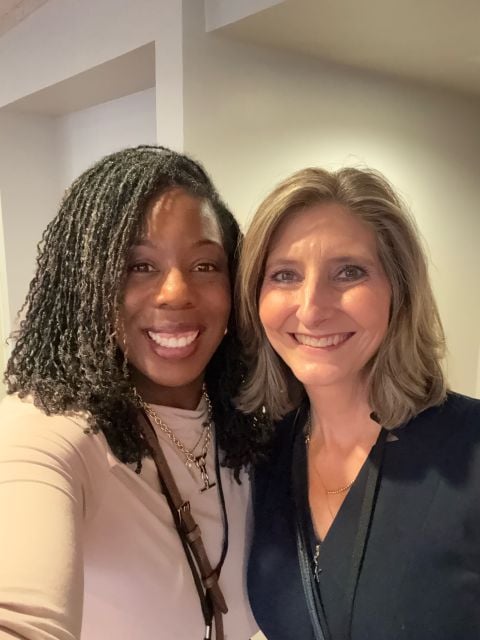 Two conference attendees smiling together
