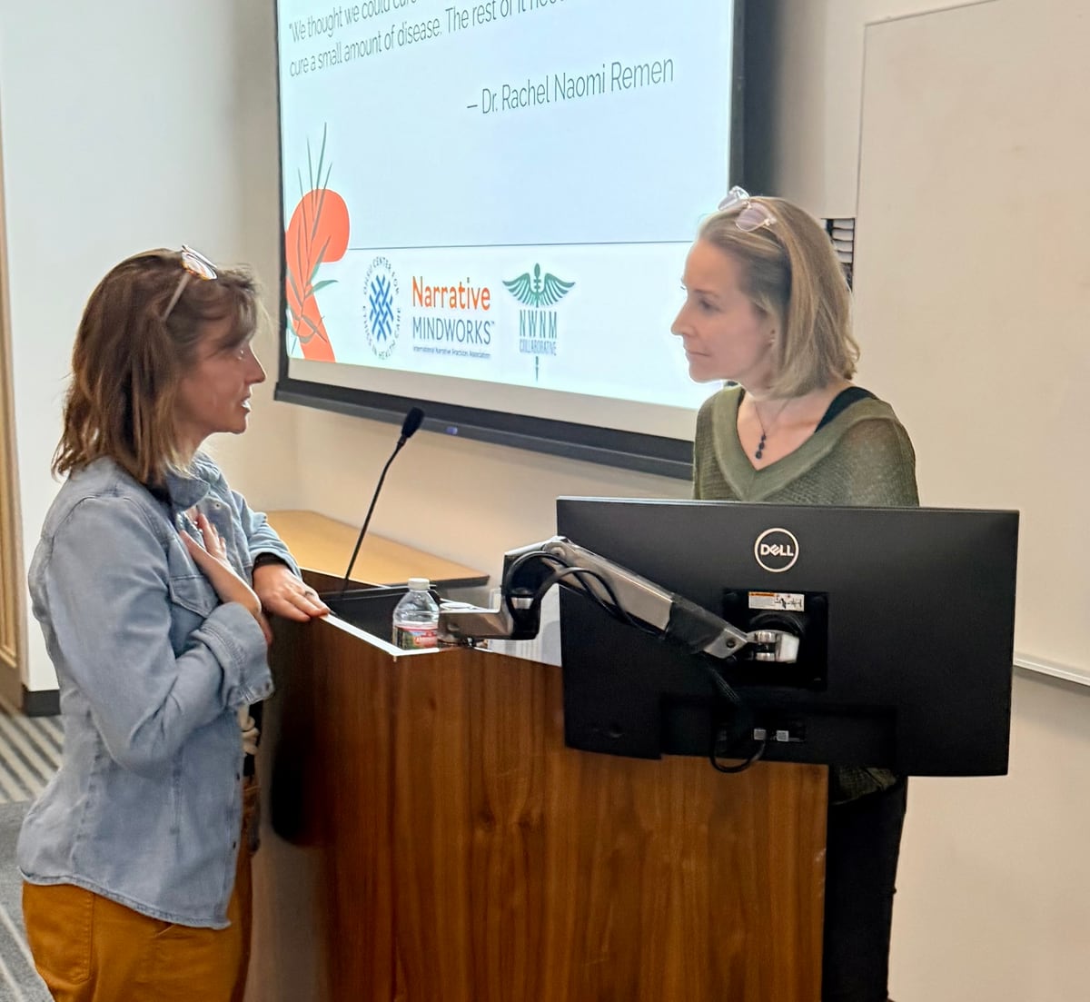 Two women in conversation beside the workshop lectern